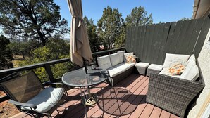 A covered patio with wicker furniture, a round table, and a cushioned bench. - Serene Sedona Studio w/ double shower and private patio with view! (Sedona)