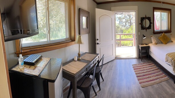 A bedroom with a bed, bedside table, lamp, and a desk with a computer. - Serene Sedona Studio w/ double shower and private patio with view! (Sedona)