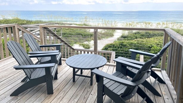 A wooden deck with Adirondack chairs and a table, overlooking a beach and ocean. - Quaint, private gulf front on North Cape, NEW kitchen and bathrooms! (Port St Joe)