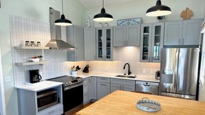 A modern kitchen with grey cabinets, a wooden island, stainless steel appliances, and pendant lighting. - Quaint, private gulf front on North Cape, NEW kitchen and bathrooms! (Port St Joe)