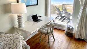 A room with a desk, a laptop, a map on the wall, and a view of the beach through a large window. - Quaint, private gulf front on North Cape, NEW kitchen and bathrooms! (Port St Joe)