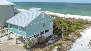 A coastal house with a metal roof, a balcony, and a view of the beach and ocean. - Quaint, private gulf front on North Cape, NEW kitchen and bathrooms! (Port St Joe)