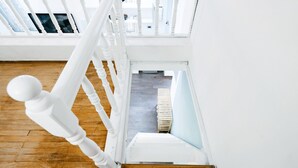 Een witte trap met een houten vloer die uitkomt op een plateau.