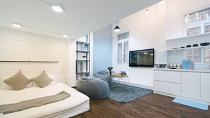 Een moderne slaapkamer met een bed, een grijze kruik, een klein bureau en een televisie.