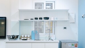 Een moderne keuken met witte kasten, een inbouwraam en een grijze koelkast.