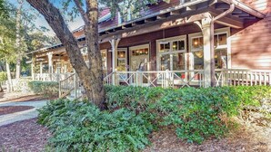 A wooden building with a covered porch, large windows, and a tree in the foreground. - 2026 Beachwood - Hosted by Moore AI Rentals (Fernandina Beach)