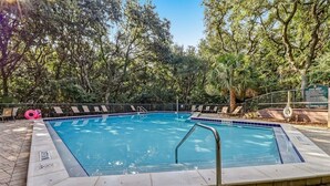 A rectangular pool with a tiled edge, surrounded by a paved deck and trees. - 2026 Beachwood - Hosted by Moore AI Rentals (Fernandina Beach)