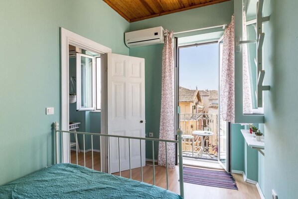 Une chambre à coucher avec un lit, une porte donnant sur un balcon et un appareil de climatisation.