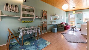 A cozy living room with a dining area, wooden ceiling, and a view of the city through large windows. - St Spyridon Cosy Apartment By Konnect (Corfu)