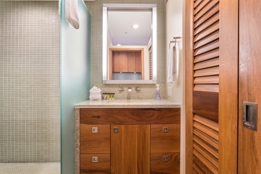 A bathroom with a wooden vanity, a mirror, and a towel rack.