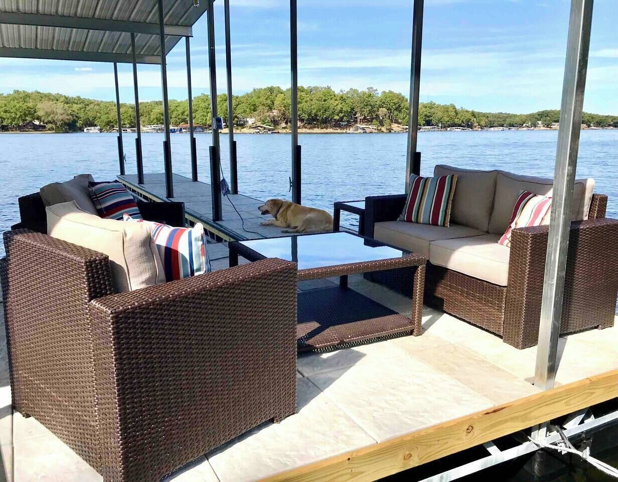 A covered outdoor seating area with wicker furniture and a dog lying on the deck.