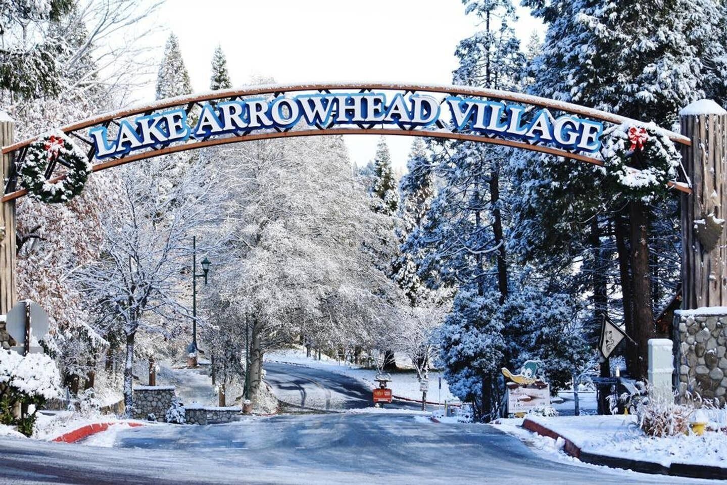 A snow-covered entrance sign for Lake Arrowhead Village.