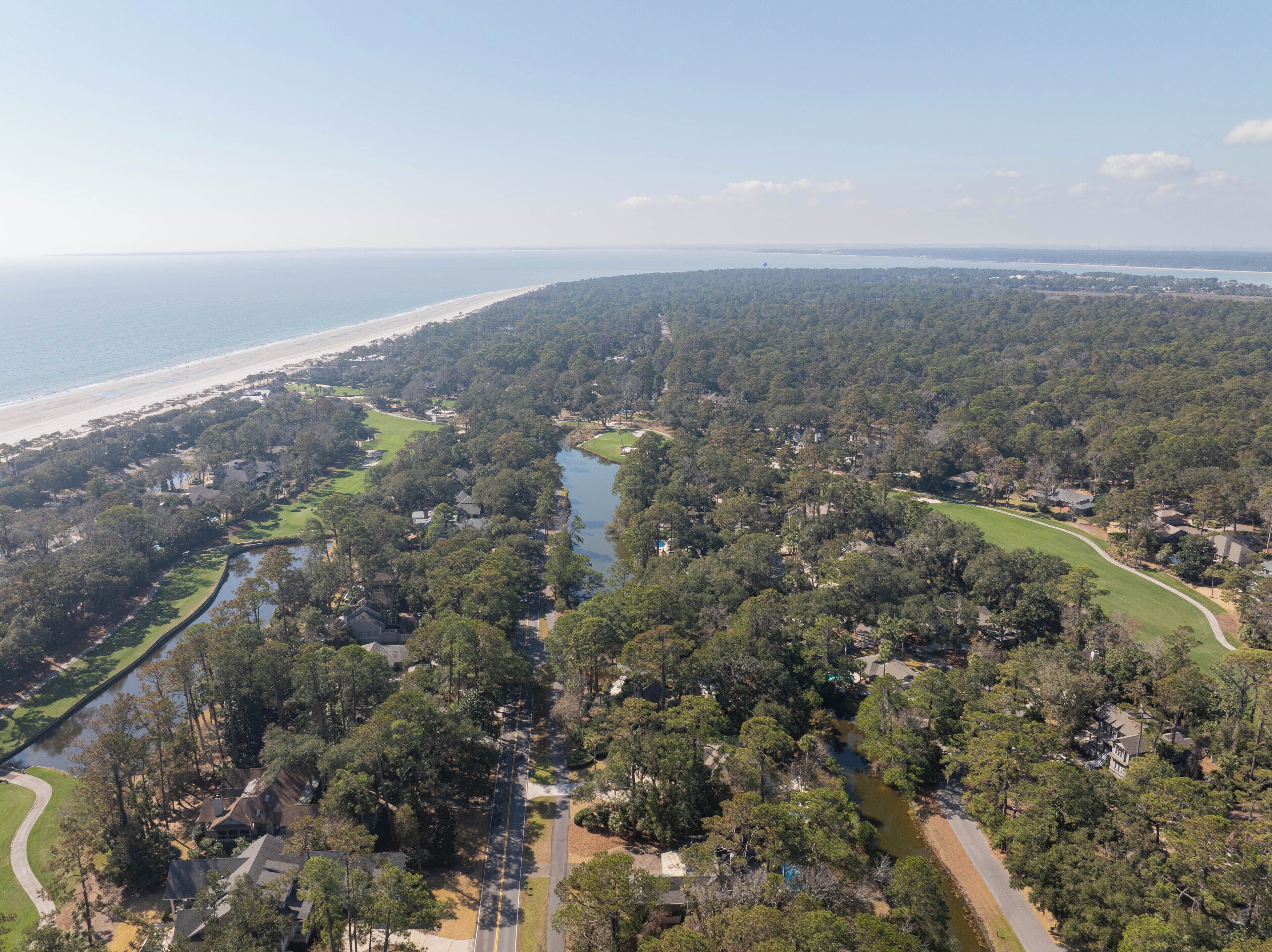 Vista aérea de una zona residencial con un río, un campo de golf y una playa.