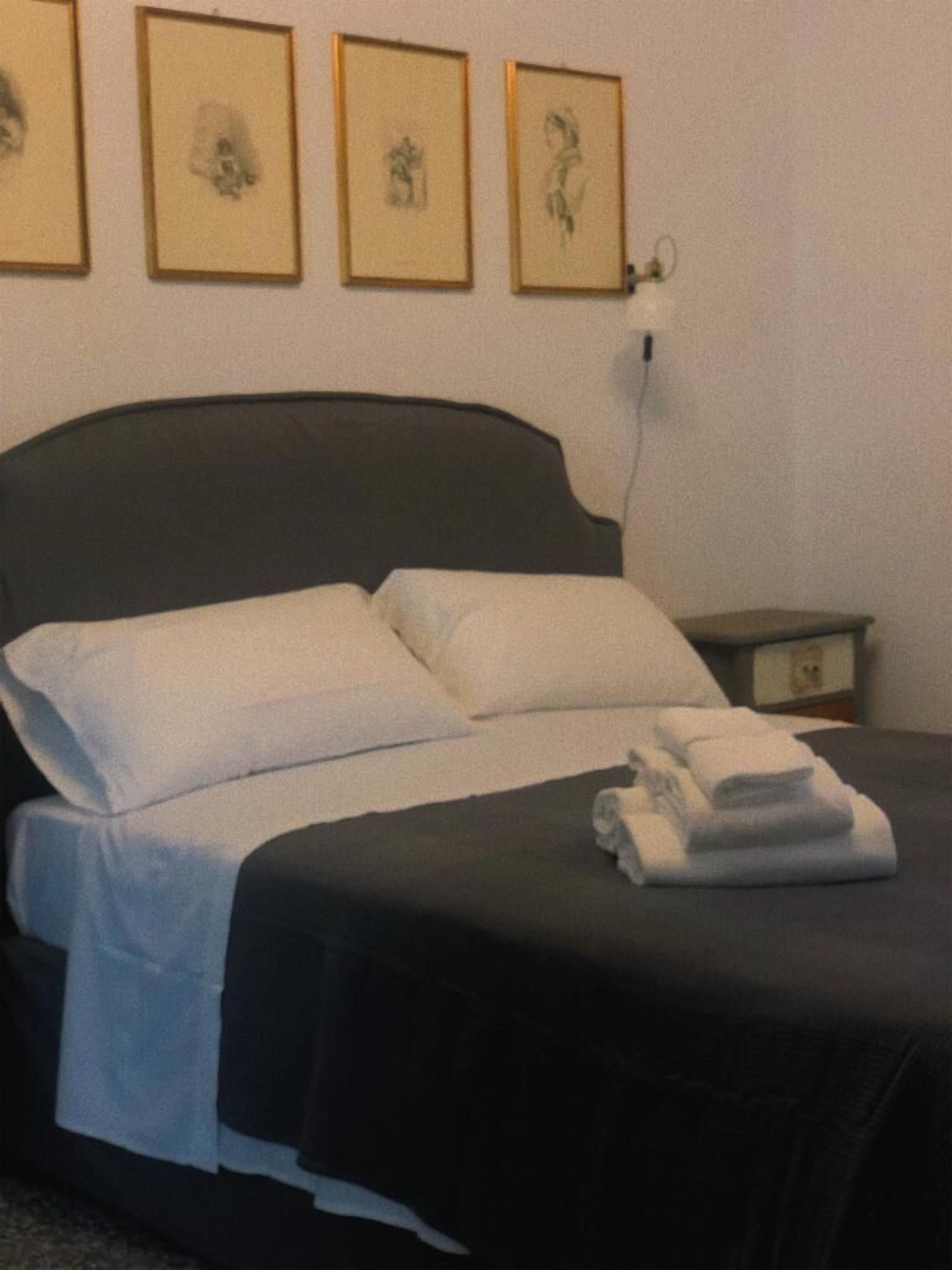 A neatly made bed with white linens, a black headboard, and a small bedside table with a lamp.