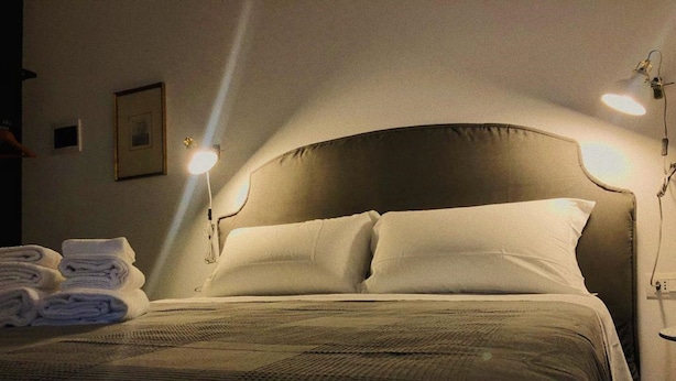 A neatly made bed with a dark headboard, white pillows, and a folded towel on the side. - Torre Tresca 2 (Bari)