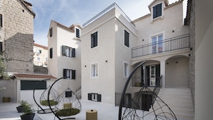 A courtyard with hanging chairs, potted plants, and a staircase leading to an upper level. - Sperone Luxury Accommodation (Split)