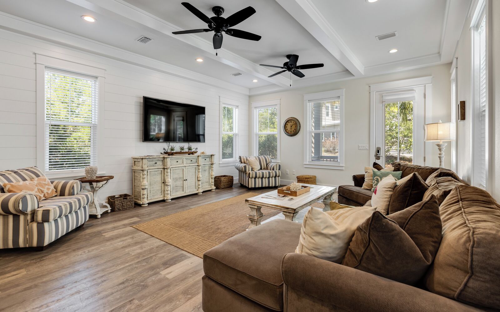 A spacious living room with a large sofa, a coffee table, and a television mounted on the wall.