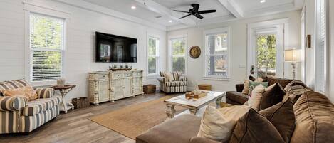 A spacious living room with a large sofa, a coffee table, and a television mounted on the wall.
