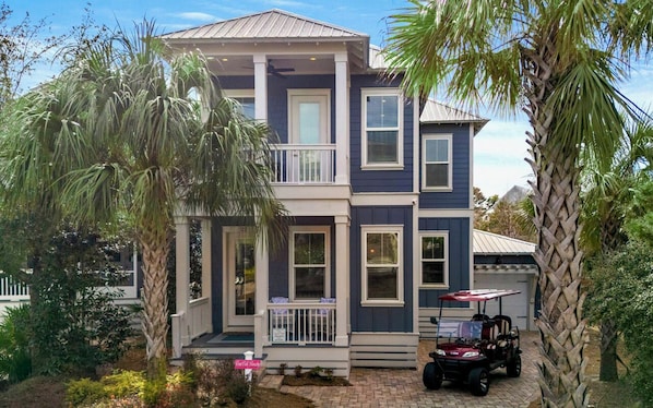A two-story house with a porch, a covered patio, and a golf cart.