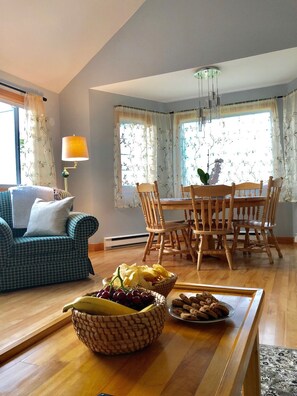 Cozy living area with a dining table for four, comfortable sofa, and large windows.