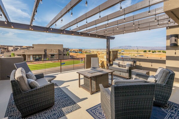 Um terraço no topo com móveis de vime, vista para um campo de beisebol e céu claro.
