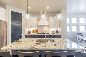 Enjoy cooking in this well-equipped kitchen with a large island, stainless steel sink, and range hood.