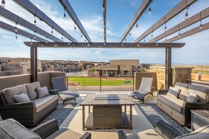 Um terraço no telhado com móveis para área externa, painéis solares e vista para um campo de beisebol.