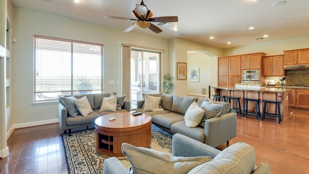 A spacious living room with a large sectional sofa, a round coffee table, and a ceiling fan. - Group-Friendly Estrella Gem: Hike, Cheer & Explore (Goodyear)