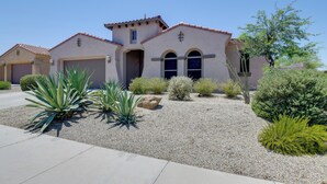 A residential building with a beige facade, a tiled roof, and a gravel driveway. - Group-Friendly Estrella Gem: Hike, Cheer & Explore (Goodyear)