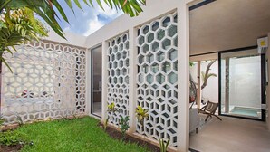 A modern house with a glass door, a white lattice wall, and a small garden.