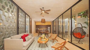 A modern living room with a sofa, chairs, a coffee table, and a ceiling fan.