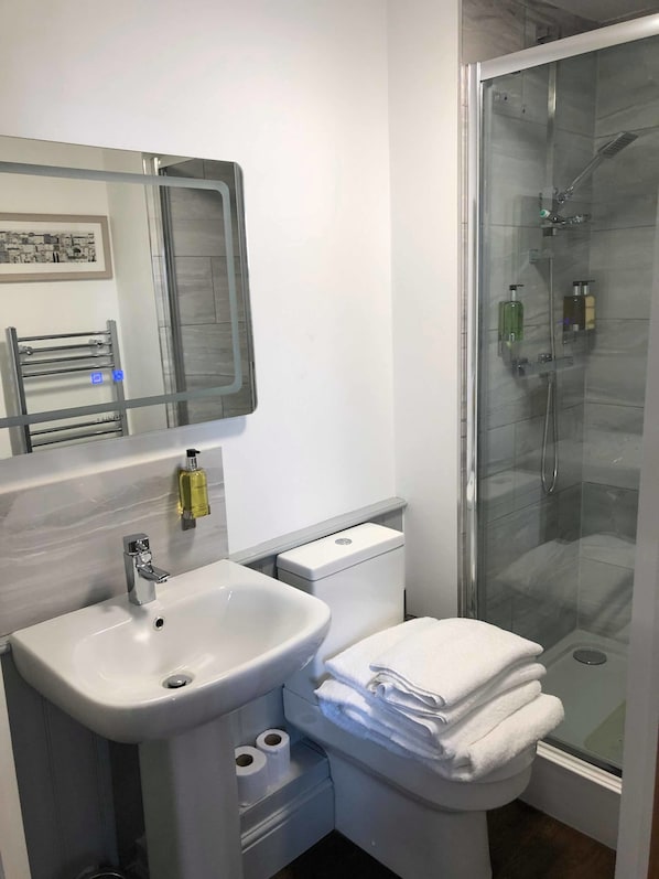 A modern bathroom with a white sink, toilet, and glass-enclosed shower. - The Wheatsheaf Inn (Nottingham)