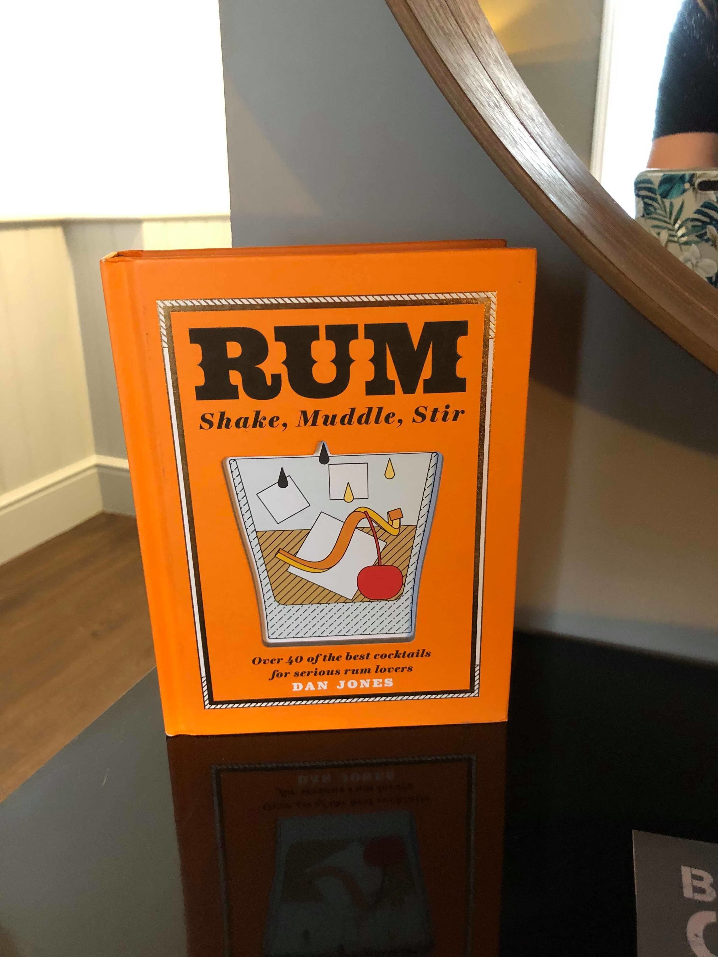 A book titled 'RUM' with a cover illustration of a cocktail shaker, a muddle, and a stirrer.