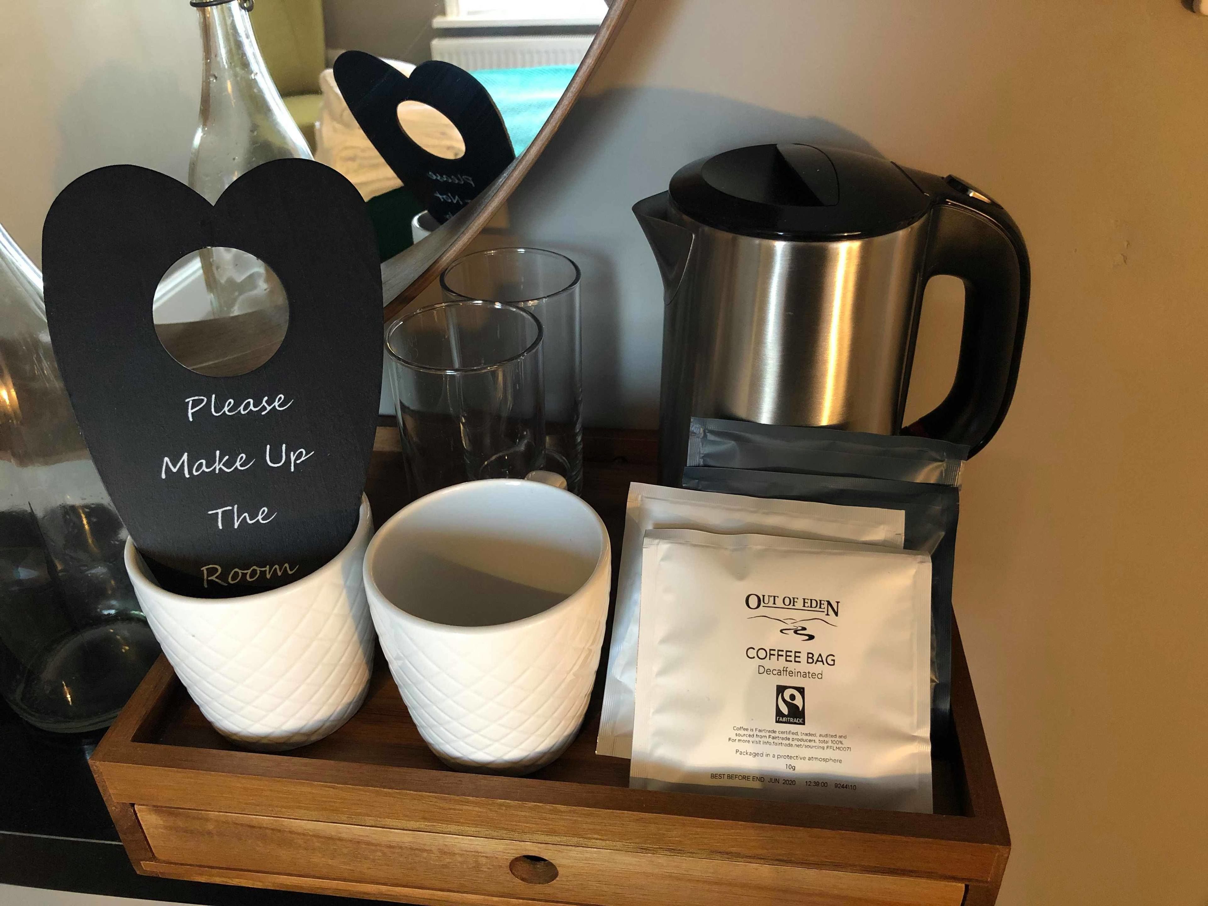 A tray with a coffee bag, two cups, a kettle, and a sign that says "Please Make Up The Room".