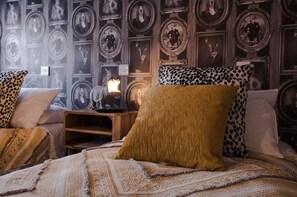A bedroom with a patterned wallpaper, a wooden nightstand, and a bed with patterned bedding. - The Wheatsheaf Inn (Nottingham)