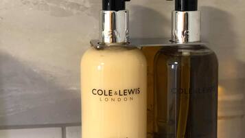 Två flaskor av Cole & Lewis London-hårinpackning står på en vägg i badrummet.