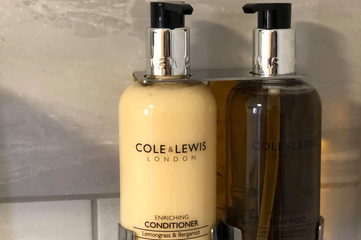 Two bottles of Cole & Lewis London conditioner on a bathroom wall.