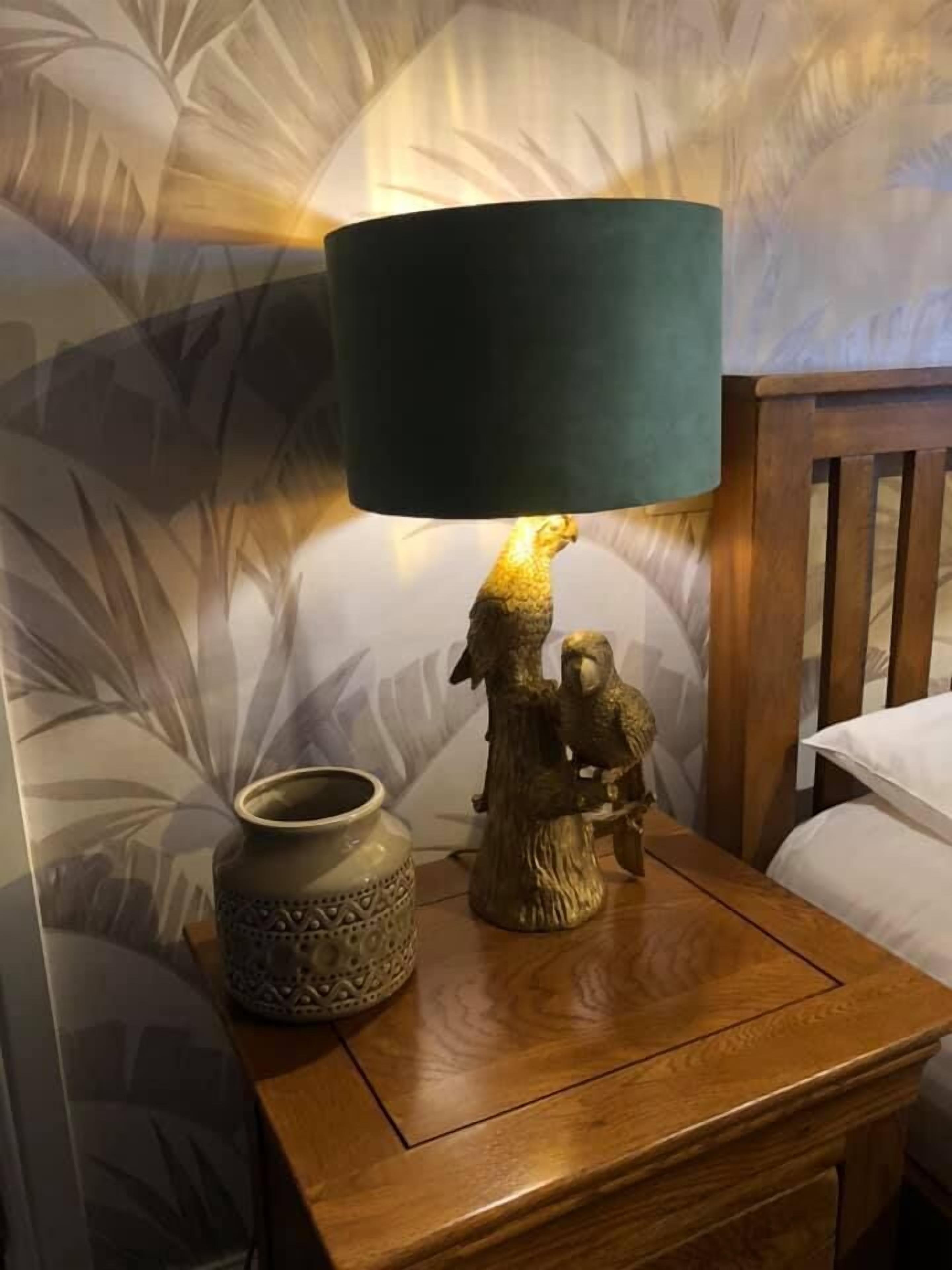 Et natbord i træ med en lampe, en dekorativ vase og en fuglefigur.