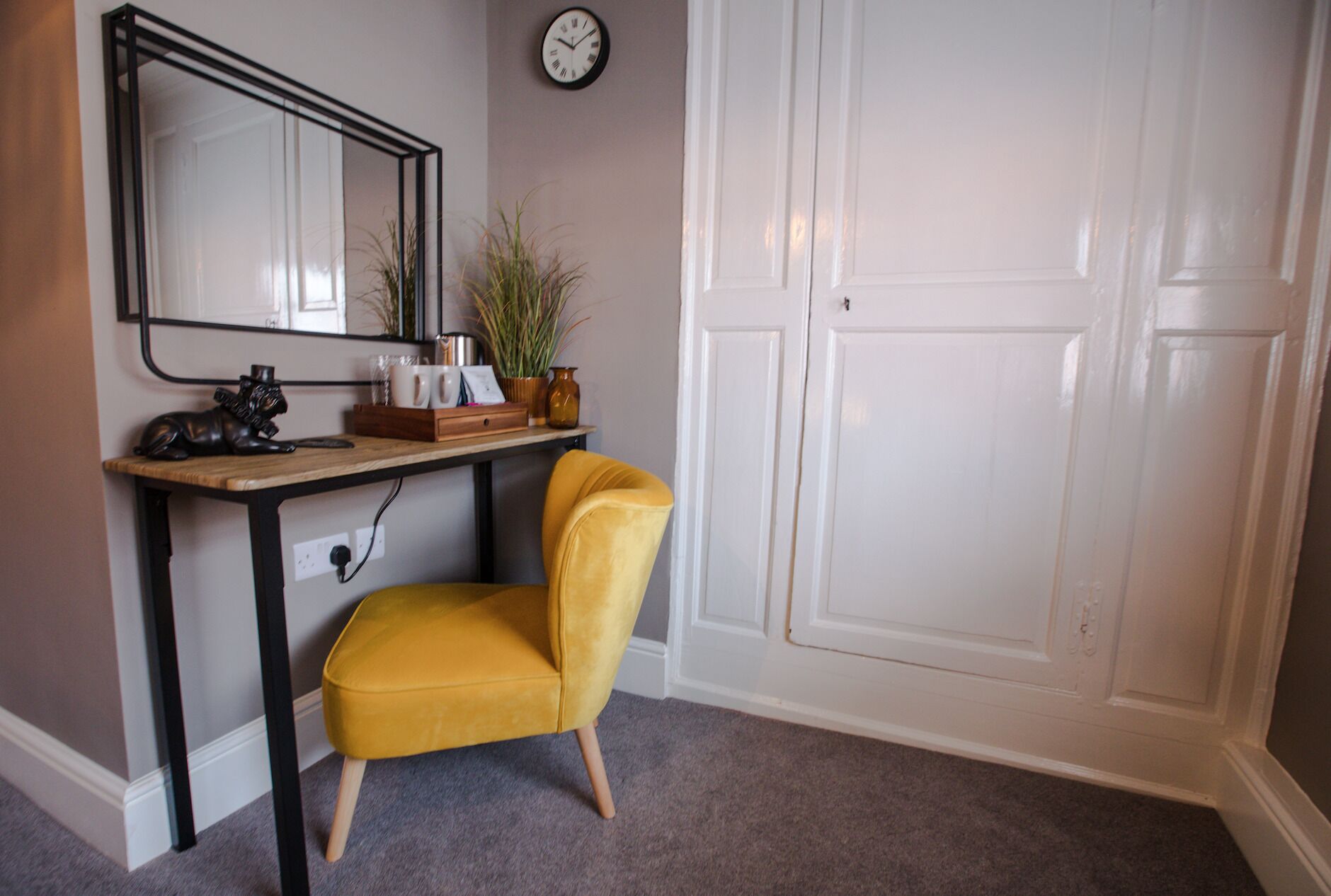 Una habitación con un escritorio, una silla, un reloj y una puerta blanca.