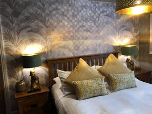 A hotel room with a bed, two nightstands, and a wall with a floral pattern.
