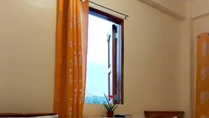 Quarto de hotel com duas camas, uma escrivaninha de madeira e uma janela com cortinas.
