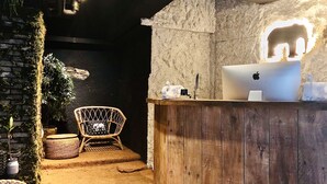 A rustic wooden reception desk with a laptop, a chair, and a wall-mounted light fixture. - Hotel Elephant (Busan)
