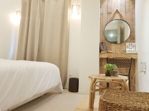 A bedroom with a bed, a small table with a plant, a chair, a round mirror, and a waste bin. - Hotel Elephant (Busan)