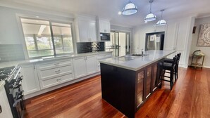 Una cocina moderna con armarios blancos, una isla grande y un refrigerador de acero inoxidable.