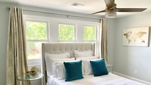 A bedroom with a large bed, a ceiling fan, and a world map on the wall.