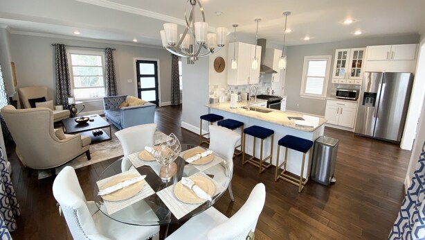 A modern kitchen with white cabinets, stainless steel appliances, and a central island with bar stools.
