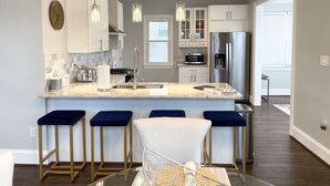 A modern kitchen with a central island, stainless steel appliances, and bar stools.