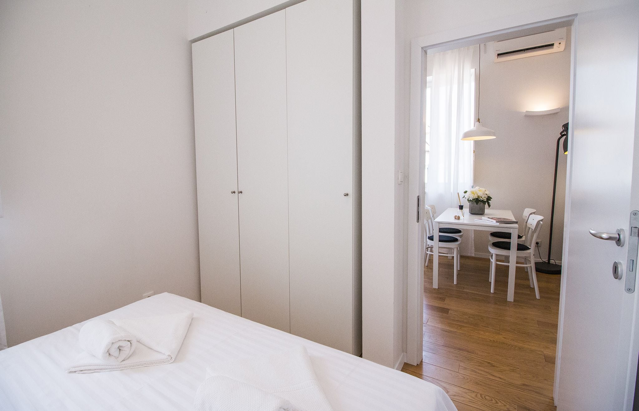 A hotel room with a bed, a desk with chairs, and a door leading to another room.