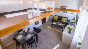A compact studio apartment with a loft bed, a dining area, a sofa, and a kitchenette. - Furioso Apartments (Split)