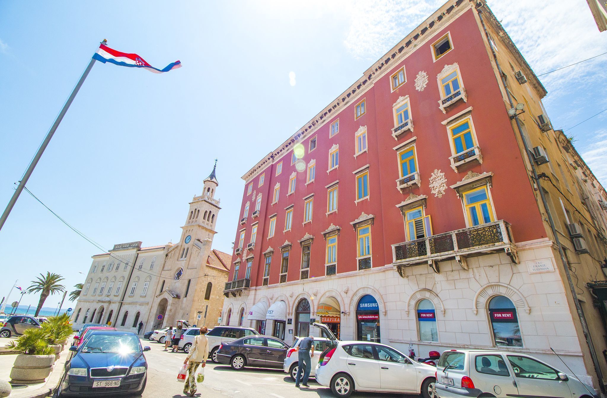 A historic building with a clock tower, multiple balconies, and ground-floor shops.